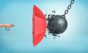 A male hand holding an open red umbrella which protects from a collision with a broken wrecking ball.